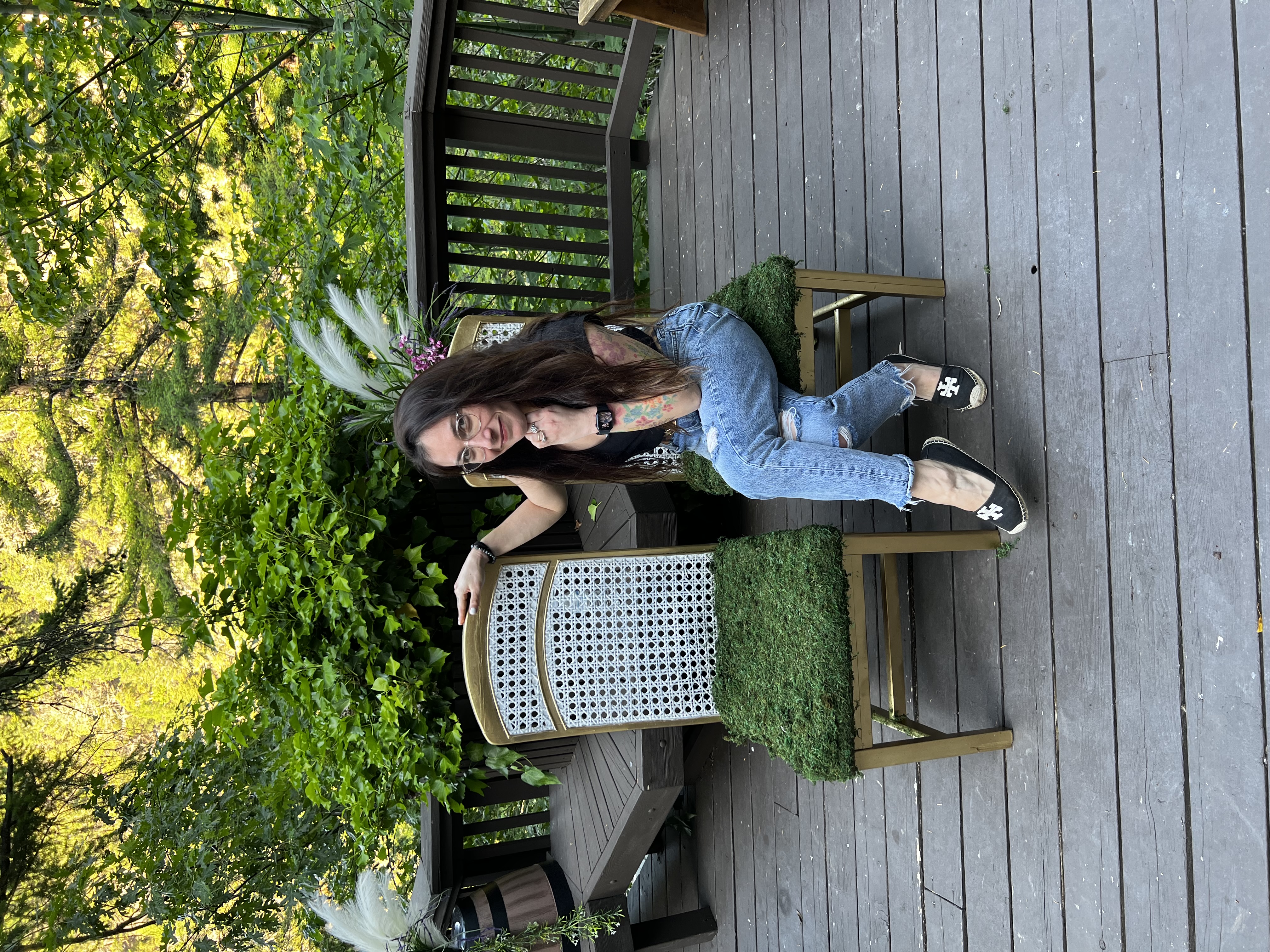 Mayra, the tarot reader behind WheelUpFortune, seated outdoors among greenery